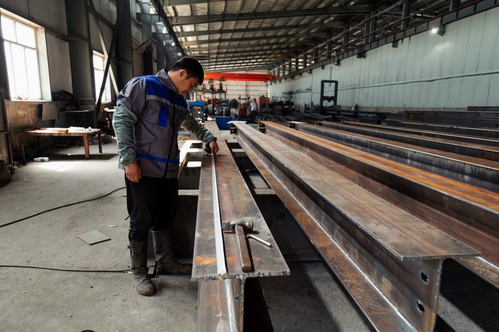 A worker inspecting steel beams for cambering in Brooklyn, NY
